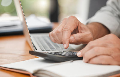 Midsection of man using laptop at table