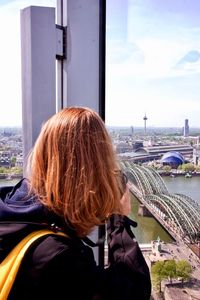 Rear view of woman in city against sky