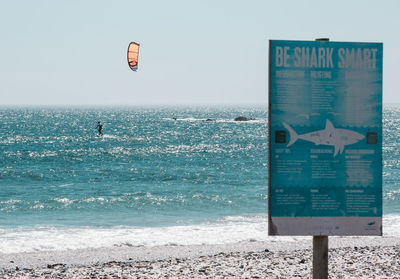 Information sign on beach against clear sky