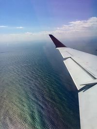 Aerial view of airplane wing over sea against sky