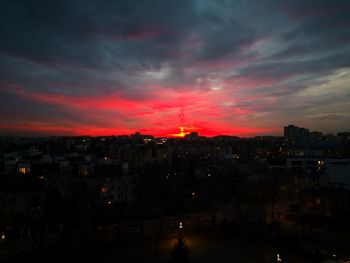 Silhouette of buildings against cloudy sky at sunset