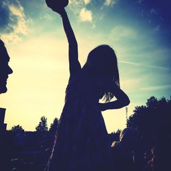 Silhouette woman with arms raised against sky during sunset