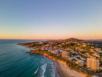 Aerial view of sea and buildings against clear sky