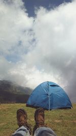 Low section of people on landscape against cloudy sky