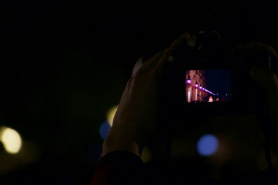 Low angle view of hand on illuminated stage against sky at night