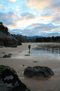 Man on beach against sky during sunset