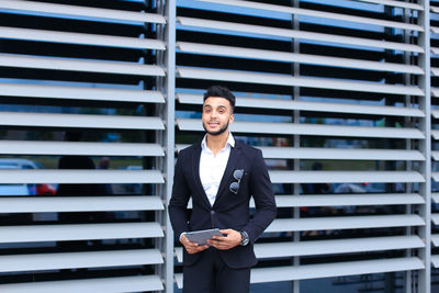 Portrait of businessman standing against wall