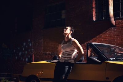 Handsome man leaning on car at street in city during night
