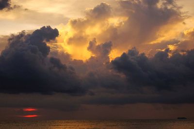 Scenic view of sea against dramatic sky during sunset