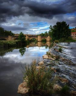 Bridge over river against cloudy sky