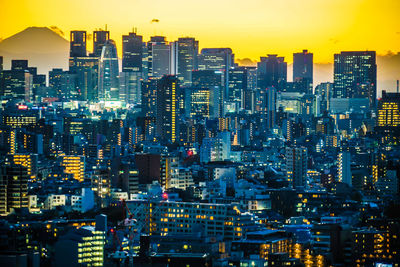 Illuminated cityscape against sky during sunset