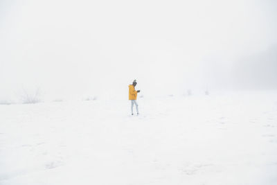 Side view full length of african american male in outerwear standing on snowy ground in winter day