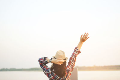 Woman with arms raised against clear sky