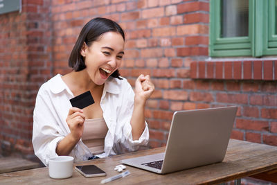 Young woman using laptop while sitting on table