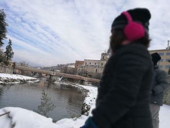 Rear view of woman photographing in city during winter