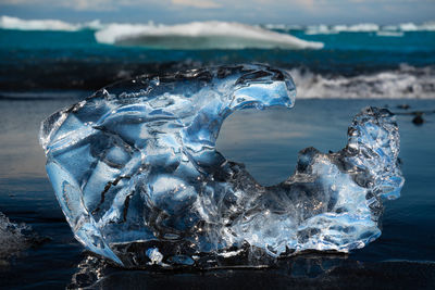 Small piece of ice melted into to a crazy formation spilled onto a black sand coast near a glacier 