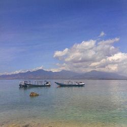 Boats in sea against cloudy sky