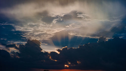 Low angle view of sunlight streaming through clouds