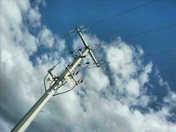 Low angle view of electricity pylon against cloudy sky