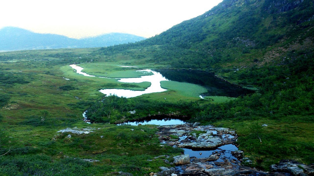 mountain, landscape, green color, grass, tranquil scene, tranquility, scenics, built structure, nature, beauty in nature, architecture, high angle view, tree, mountain range, water, hill, day, building exterior, non-urban scene, idyllic