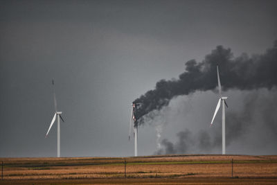 Wind turbines on field against sky