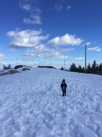 Rear view of person walking on snow covered field