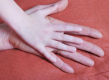 Close-up of parent and child hands on bed