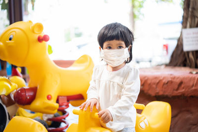 Girl wearing face mask sitting on rocking horse