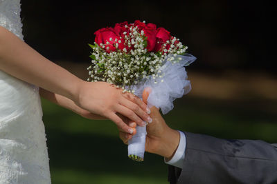 Close-up of groom hand giving bouquet to bride