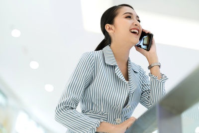 Low angle view of young woman using mobile phone