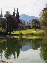 Scenic view of lake by trees and buildings against sky