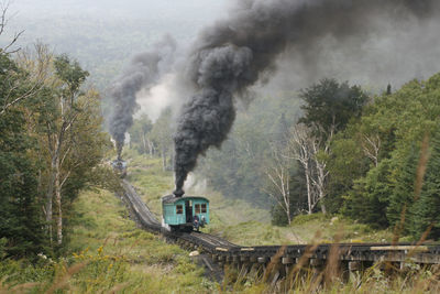 Two steam locomotives of mount washington cog railway pusing coaches to the summit at good weather