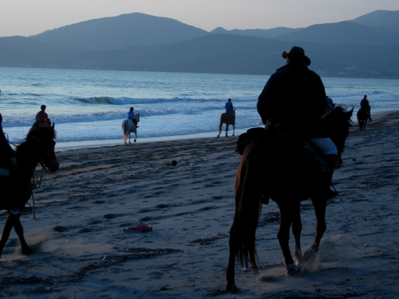 PEOPLE RIDING HORSE ON BEACH