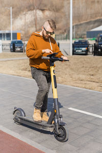 Man riding push scooter on road