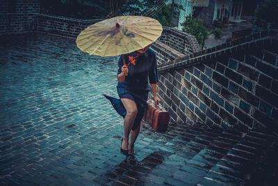 Full length of woman holding umbrella during rainy season