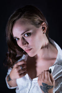 Portrait of young woman showing wounds on neck against black background