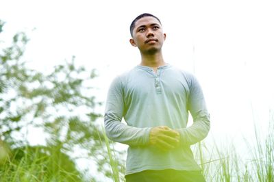 Low angle view of young man looking away against sky