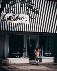 Full length rear view of woman standing against sign