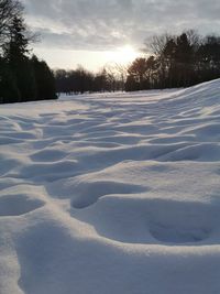 Snow covered field against sky during winter