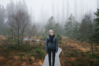 Woman standing in forest during winter