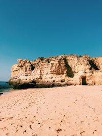 Rocks on beach against clear blue sky