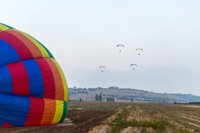 Hot air balloons flying over field against sky