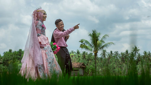 Smiling man pointing away while standing with woman outdoors