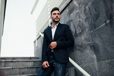 Man in suit standing by wall