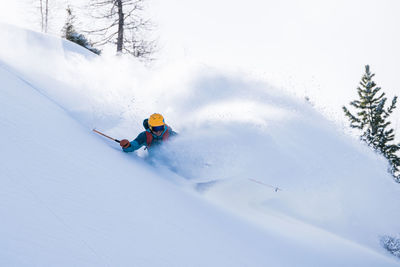 Man skiing on snowcapped mountain against sky