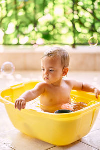 Girl with toys sitting in bathtub