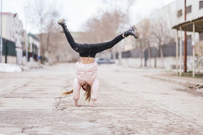 Girl doing handstand on road against sky