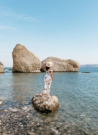 Rear view image of woman in long dress standing on beautiful beach on pag island in croatia.