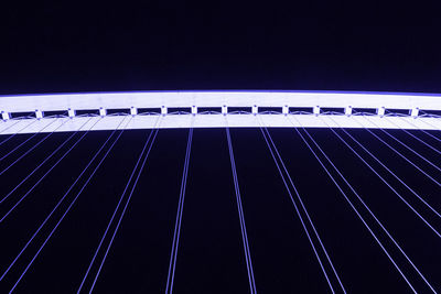 Low angle view of illuminated bridge against blue sky