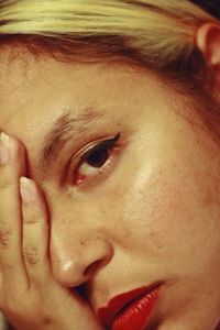 Close-up portrait of young woman with hand on face